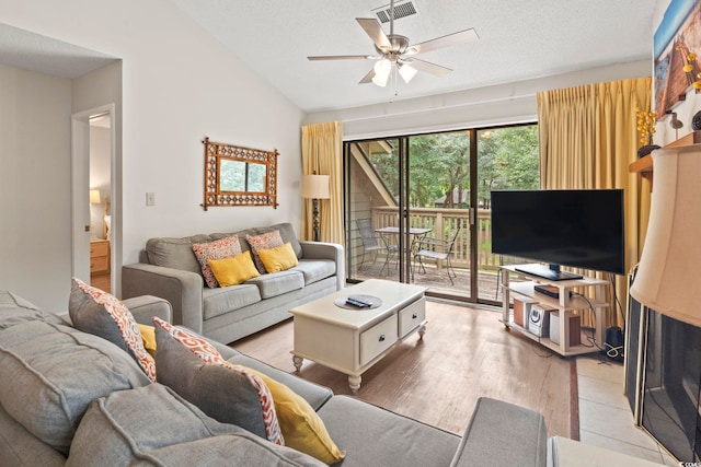 living room featuring a textured ceiling, ceiling fan, light hardwood / wood-style flooring, and lofted ceiling