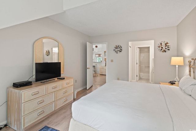 bedroom featuring connected bathroom and light hardwood / wood-style floors