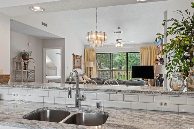 kitchen featuring a textured ceiling, ceiling fan with notable chandelier, sink, decorative light fixtures, and lofted ceiling