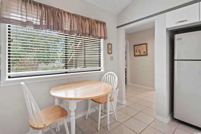 tiled dining room featuring lofted ceiling