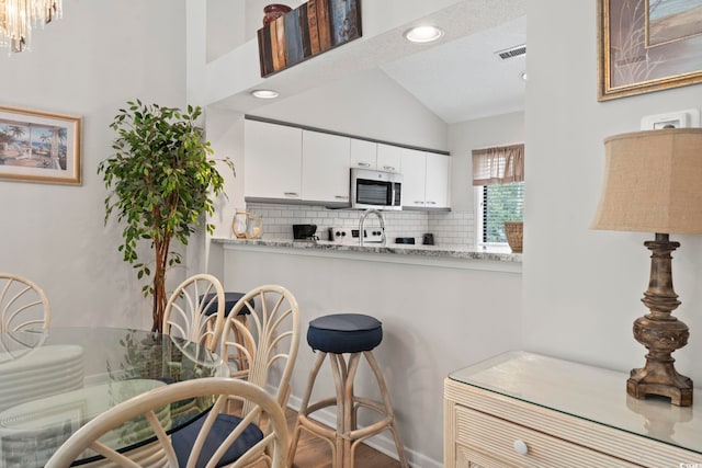 kitchen featuring tasteful backsplash, light stone counters, hardwood / wood-style floors, a textured ceiling, and white cabinets