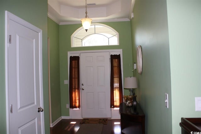 foyer with hardwood / wood-style floors, a raised ceiling, and ornamental molding