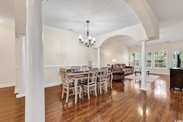 dining area with a textured ceiling, decorative columns, dark wood-type flooring, and a chandelier