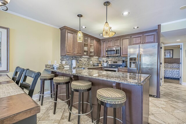 kitchen featuring stone counters, appliances with stainless steel finishes, decorative light fixtures, sink, and kitchen peninsula