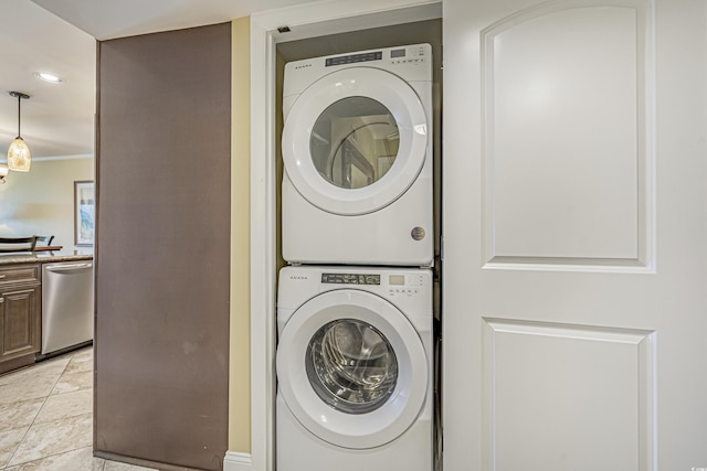 washroom featuring light tile patterned floors, crown molding, and stacked washing maching and dryer