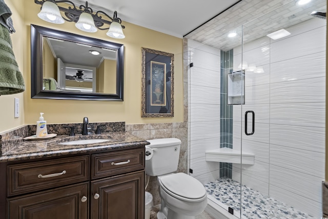 bathroom with toilet, tile walls, vanity, and a shower with shower door