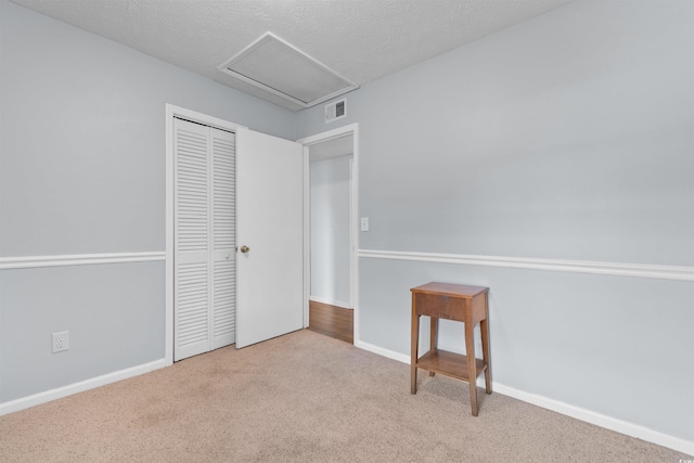 unfurnished bedroom featuring light carpet, a textured ceiling, and a closet