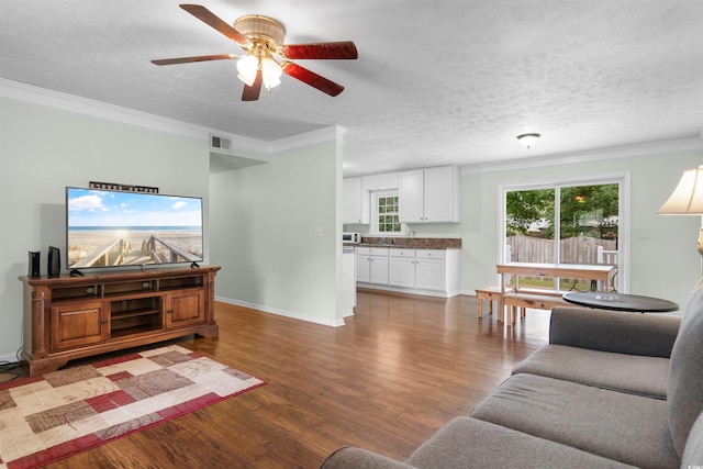 living room with ceiling fan, crown molding, hardwood / wood-style floors, and a textured ceiling