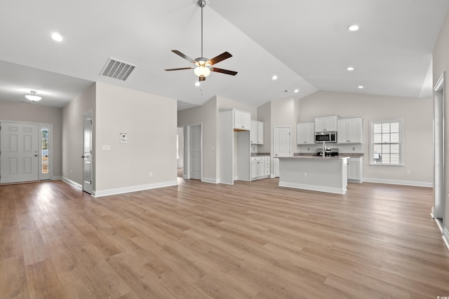 unfurnished living room with vaulted ceiling, baseboards, visible vents, and light wood-style floors