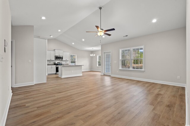 unfurnished living room with lofted ceiling, light wood-style flooring, recessed lighting, and ceiling fan with notable chandelier