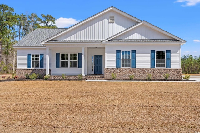 view of front of home with brick siding, a front lawn, and roof with shingles