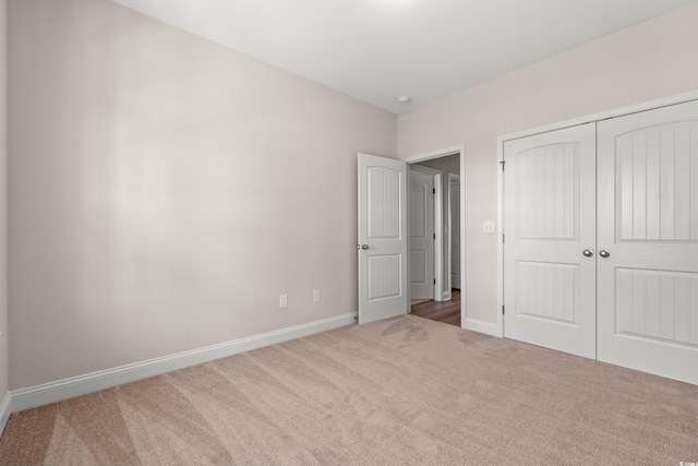 unfurnished bedroom featuring carpet floors, baseboards, and a closet