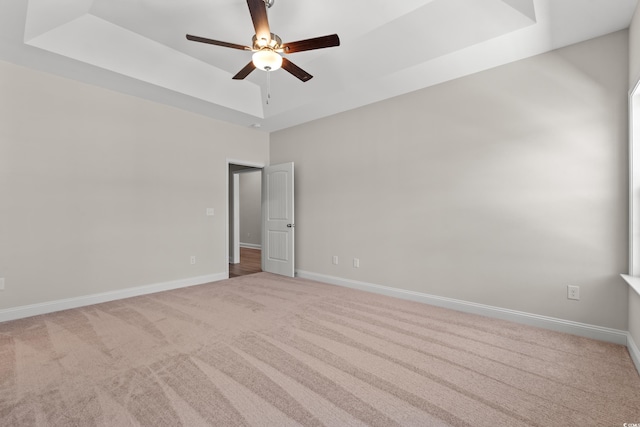 unfurnished room with carpet, a raised ceiling, ceiling fan, and baseboards