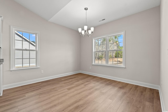 spare room featuring baseboards, light wood-style flooring, visible vents, and a healthy amount of sunlight