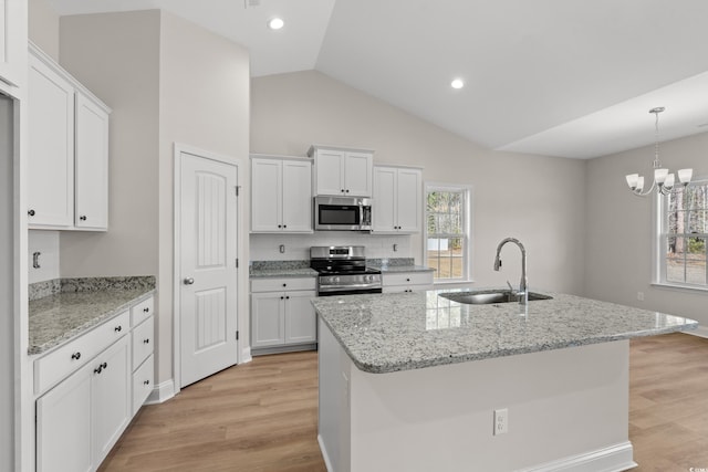 kitchen with white cabinets, lofted ceiling, stainless steel appliances, light wood-style floors, and a sink