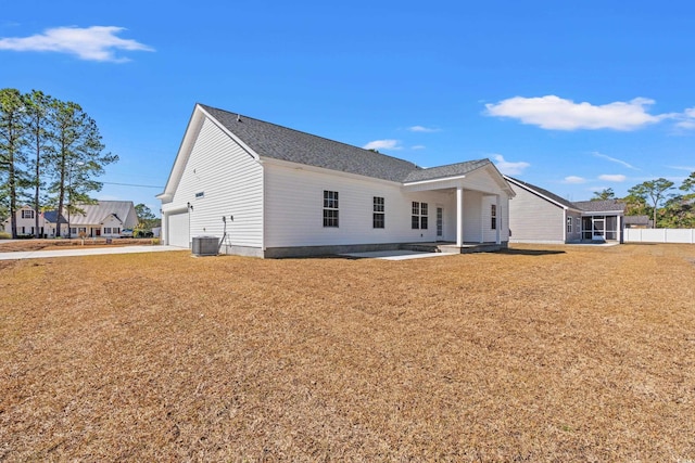 rear view of property featuring central air condition unit, a patio area, a garage, and a lawn