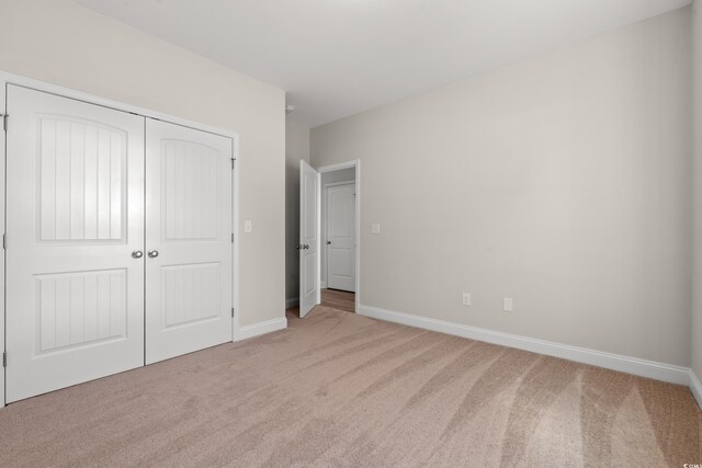 unfurnished bedroom featuring a closet, baseboards, and carpet flooring