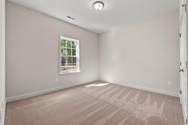 carpeted spare room with visible vents and baseboards