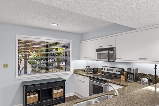 kitchen with dark wood-type flooring, sink, a textured ceiling, white cabinetry, and stainless steel appliances