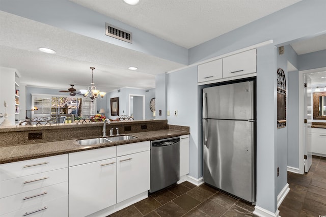 kitchen with appliances with stainless steel finishes, a textured ceiling, white cabinetry, and sink