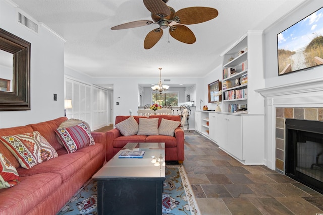 living room with a fireplace, built in shelves, a textured ceiling, and ornamental molding