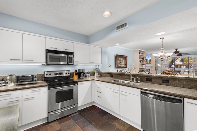 kitchen featuring appliances with stainless steel finishes, an inviting chandelier, white cabinetry, and sink