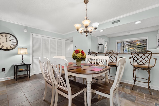 dining room with a chandelier, a textured ceiling, and ornamental molding