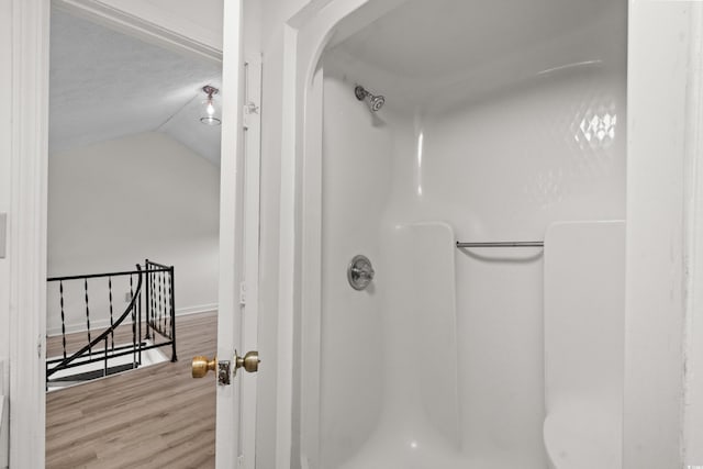 bathroom featuring lofted ceiling, a shower, wood-type flooring, and a textured ceiling