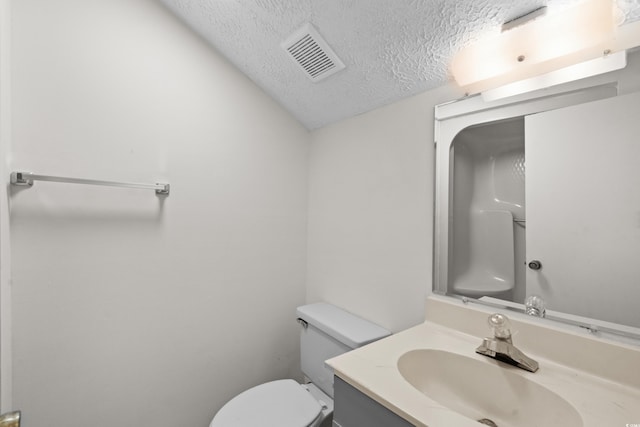 bathroom featuring toilet, a textured ceiling, and vanity