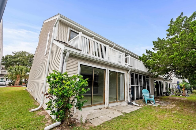 back of house with a balcony and a yard