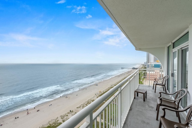 balcony with a water view and a view of the beach