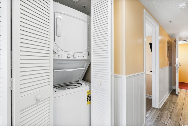 laundry area with stacked washing maching and dryer and a textured ceiling