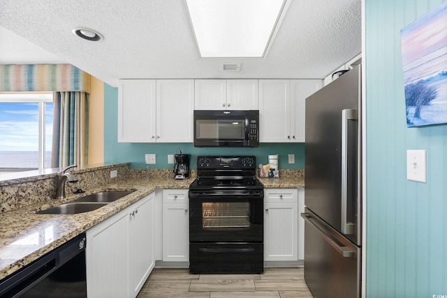 kitchen featuring sink, white cabinetry, light stone counters, a textured ceiling, and black appliances