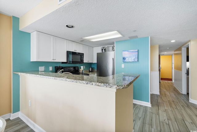 kitchen featuring a textured ceiling, black appliances, kitchen peninsula, and white cabinets