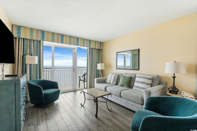 living room featuring hardwood / wood-style flooring, a textured ceiling, and a water view