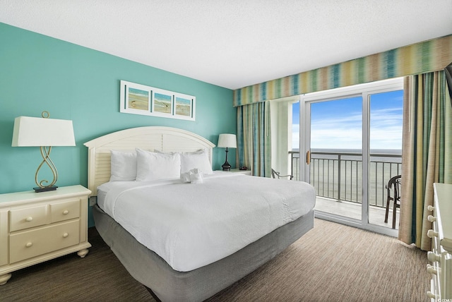 bedroom featuring a water view, access to exterior, and a textured ceiling