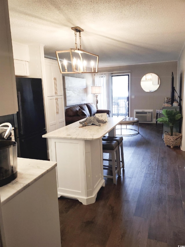 kitchen featuring light stone counters, a center island, white cabinetry, hanging light fixtures, and dark hardwood / wood-style flooring