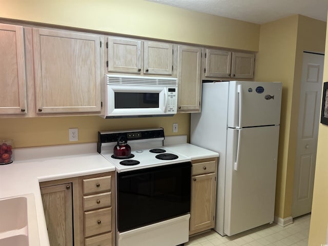 kitchen featuring light brown cabinets, white appliances, and sink