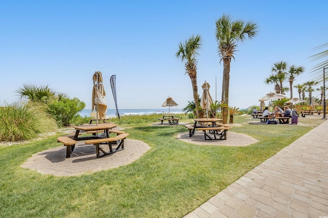 view of community featuring a lawn, a water view, and a fire pit