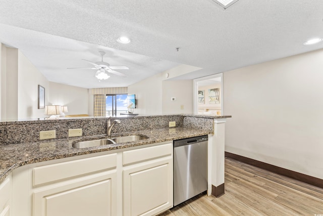 kitchen featuring light wood-type flooring, ceiling fan, dark stone counters, stainless steel dishwasher, and sink