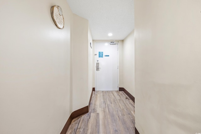 hall with a textured ceiling and light hardwood / wood-style floors