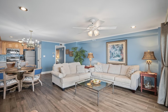 living room with ceiling fan with notable chandelier, hardwood / wood-style flooring, and ornamental molding