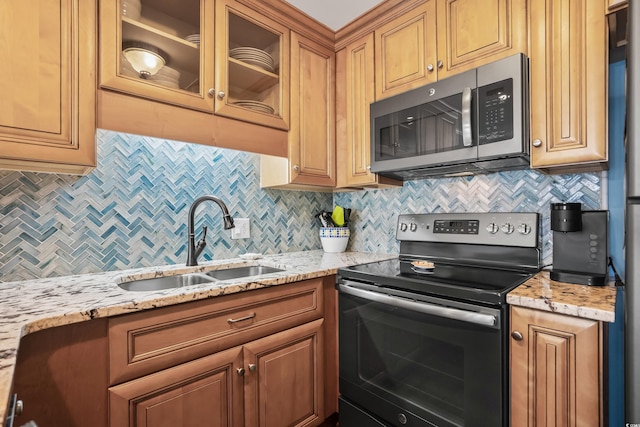 kitchen with light stone countertops, stainless steel appliances, decorative backsplash, and sink