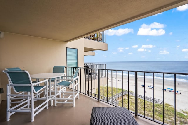 balcony with a water view and a view of the beach