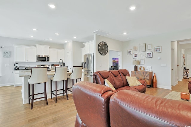 living room featuring sink and light hardwood / wood-style floors