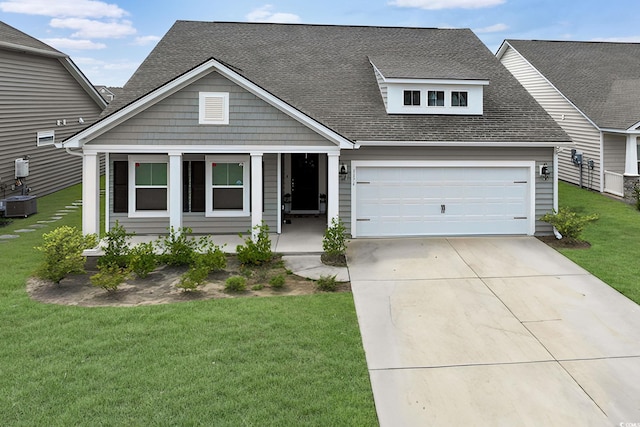 view of front of home with a front yard, central air condition unit, and a garage