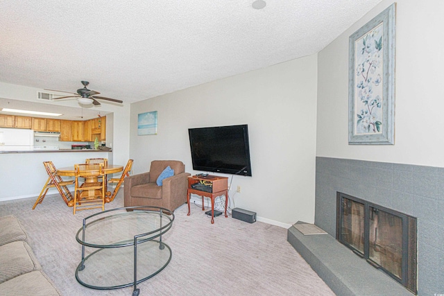 carpeted living room featuring ceiling fan, a fireplace, and a textured ceiling