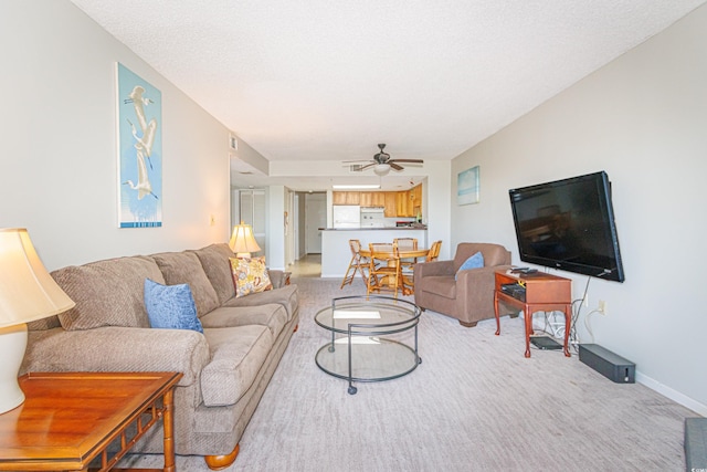 carpeted living room with ceiling fan and a textured ceiling