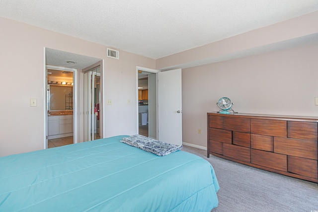 bedroom featuring light colored carpet, a textured ceiling, and connected bathroom