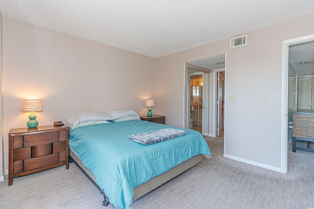 carpeted bedroom with a textured ceiling and connected bathroom